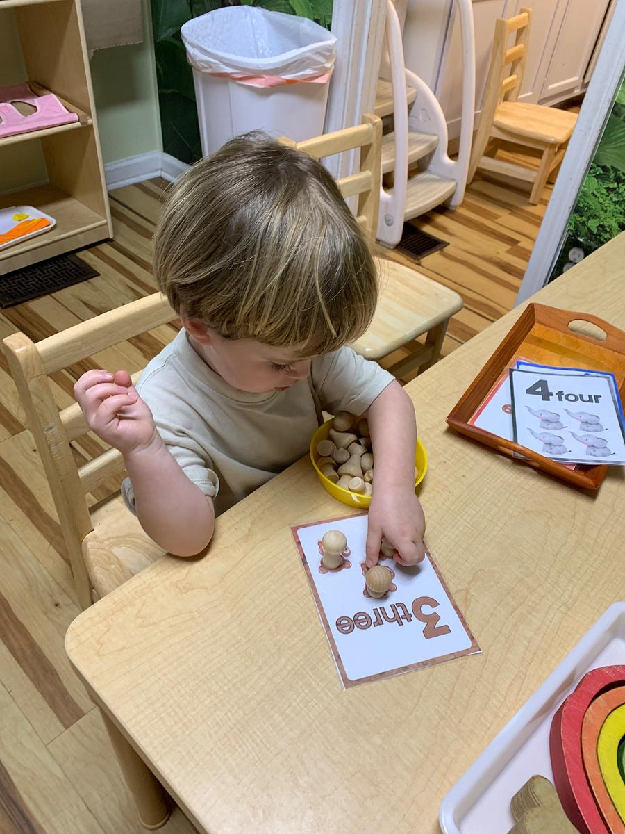 A toddler engaging with a counting activity at a table.
